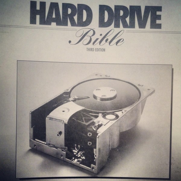 Faded monochrome book cover of the Hard Drive Bible: Third Edition, with a picture of a very old, and very large, at least 5 inches high, hard disk drive from the 80s/early 90s. The Hard Drive Bible was a series of reference books that featured configurations, manufacturer parameters and specs for hundreds of disk drives, optical drives and storage devices of the time.