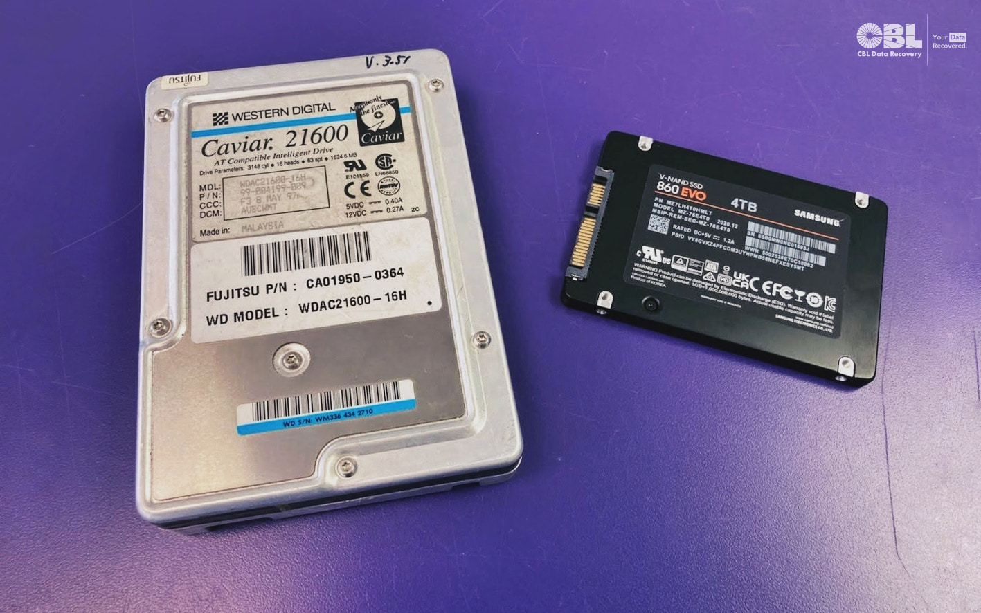 Two drives on a purple counter at CBL Data Recovery: a western digital caviar 21600 from 1997 and a Samsung EVO 4TB SSD from 2020.